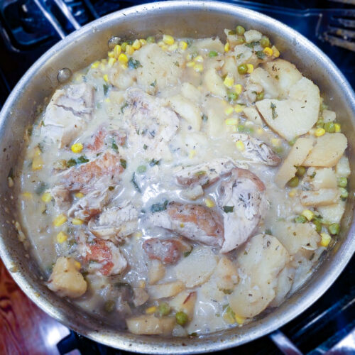One-pan creamy chicken and potato skillet with corn and peas, simmering in a bone broth and Fairlife milk sauce.